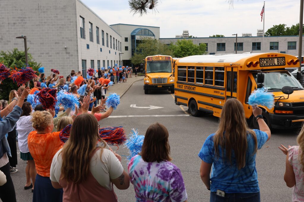 school staff waving to buses