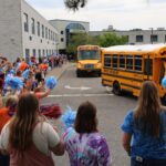 school staff waving to buses