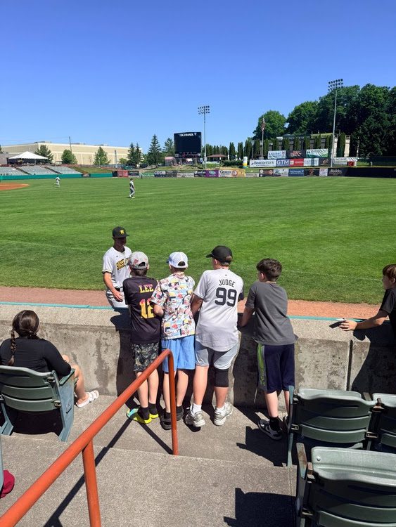 four boys meeting baseball player near home plate.